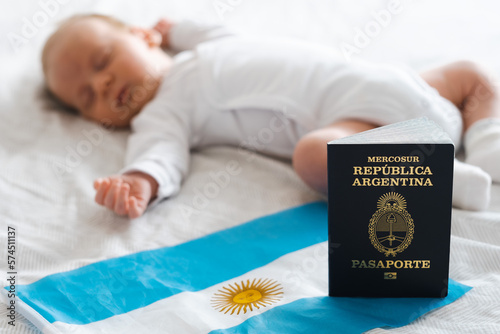 Argentinean passport and flag on background of cute caucasian newborn baby sleeping lying on bed. Concept of getting citizenship, childbirth, delivery in Argentine.
