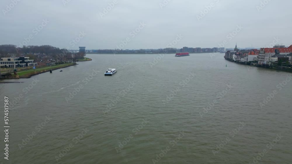 Aerial Flying Over Oude Maas On Cloudy Overcast Day With Boat Sailing Past And Container Ship Approaching In Distance Background Aerial Flying Over Oude Maas On Cloudy Overcast Day With Boat Sailing Past And Container Ship Approaching In Distance Background