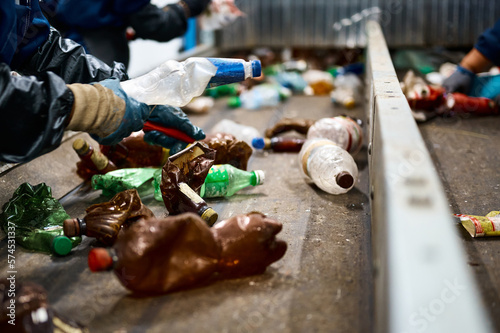 Fototapeta Naklejka Na Ścianę i Meble -  Worker sorts trash on conveyor belt at waste recycling plant