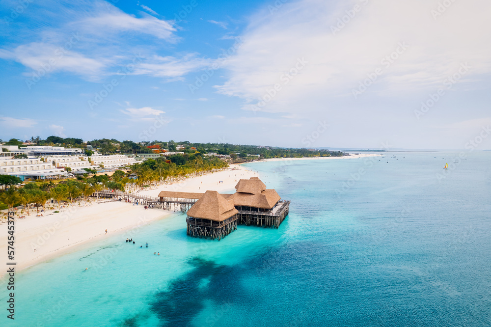 Fototapeta premium This drone shot of Nungwi Beach in Zanzibar captures the incredible beauty of the shoreline, with crystal-clear waters and golden sand providing a picture-perfect view.