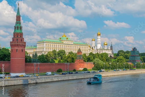 View of Kremlin with Vodovzvodnaya tower, Grand Kremlin Palace from repaired Bolshoy Kamenny Bridge in Moscow city on sunny summer day. Cruise ship sails on the Moscow river