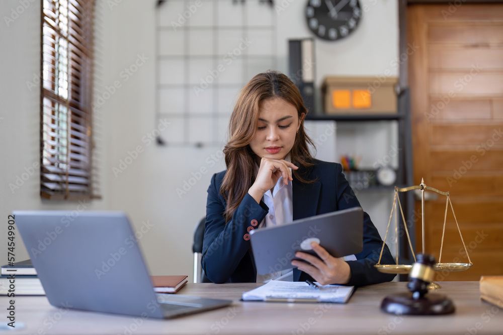 Attractive young lawyer in office Business woman and lawyers discussing contract papers with brass scale on wooden desk in office. Law, legal services, advice, Justice and real estate concept Attractive young lawyer in office Business woman and lawyers discussing contract papers with brass scale on wooden desk in office. Law, legal services, advice, Justice and real estate concept