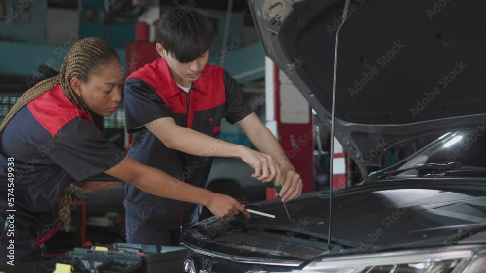 Auto service, repair, maintenance concept. Mechanic checks the car at the service station. Service maintenance of industrial to engine repair.African american woman and asian engineer . Auto service, repair, maintenance concept. Mechanic checks the car at the service station. Service maintenance of industrial to engine repair.African american woman and asian engineer .