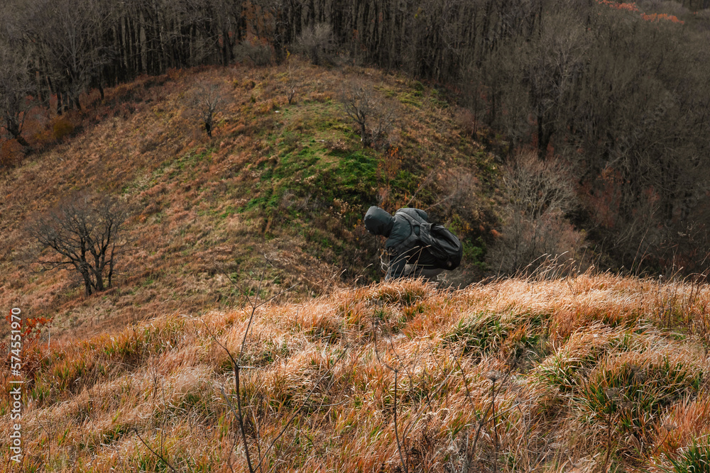 A young man with a backpack descends from the top of the mountain. A man going hiking in the Caucasus mountains. with a heavy backpack. Lifestyle travel, the concept of hiking. A young man with a backpack descends from the top of the mountain. A man going hiking in the Caucasus mountains. with a heavy backpack. Lifestyle travel, the concept of hiking.