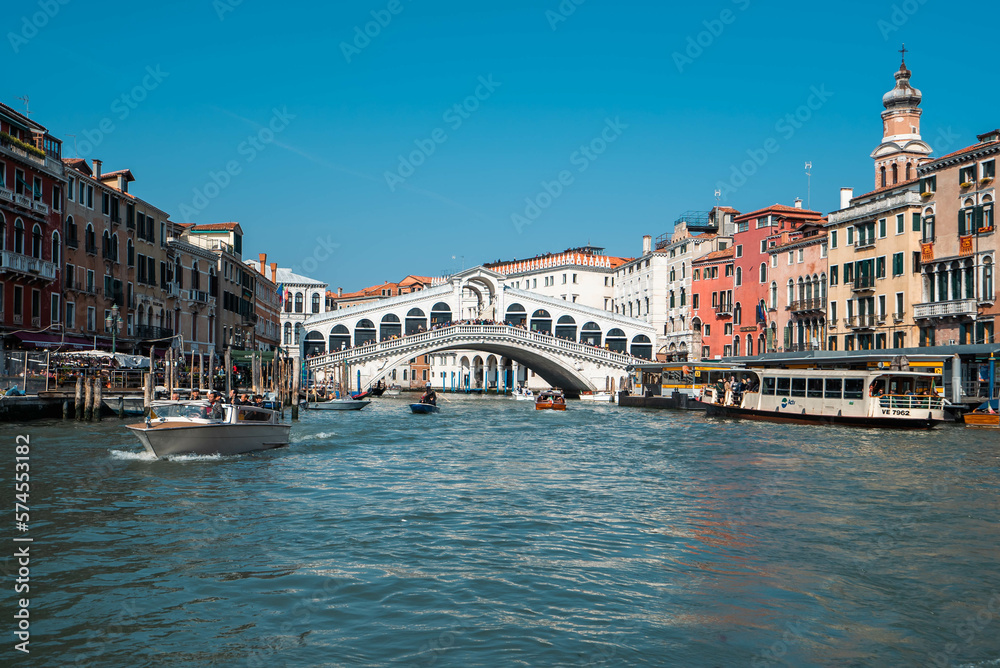 The Grand Canal and Rialto Bridge are lined on either side by Venetian Buildings with local water transport in Venice, Italy.