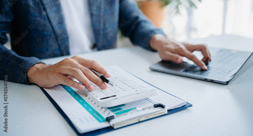 Women counting coins on calculator taking from the piggy bank. hand holding pen working on calculator to calculate on desk about cost Women counting coins on calculator taking from the piggy bank. hand holding pen working on calculator to calculate on desk about cost