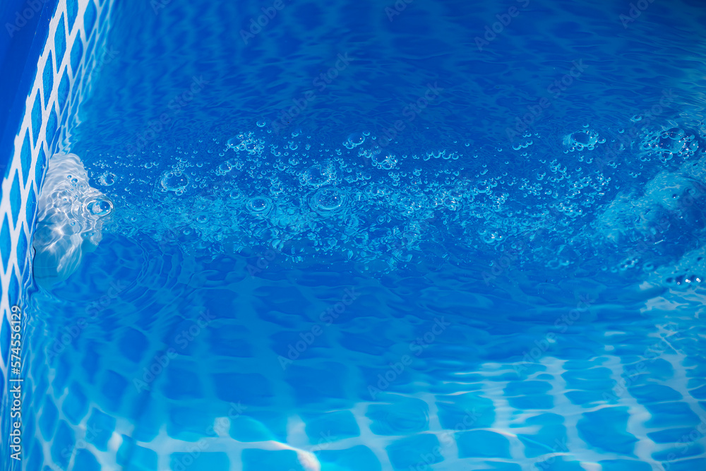 Air bubbles from jacuzzi jet in blue water in a pool, bubbly blue clean