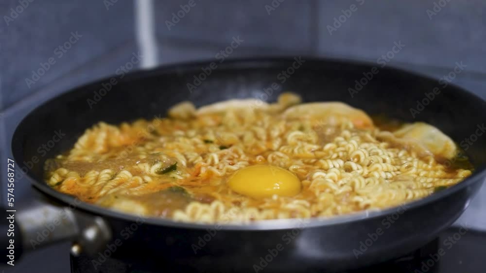 Ramen, eggs, and dumplings are being cooked in the pot. Ramen, eggs, and dumplings are being cooked in the pot.