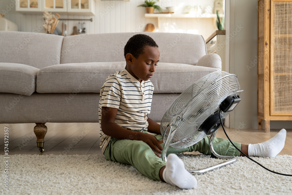 Curious child African American boy sitting on floor touching electric ...