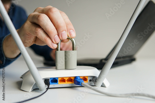 High speed wi-fi router with lock. Man using laptop on the background. Password protected wifi network and internet censorship concept.
