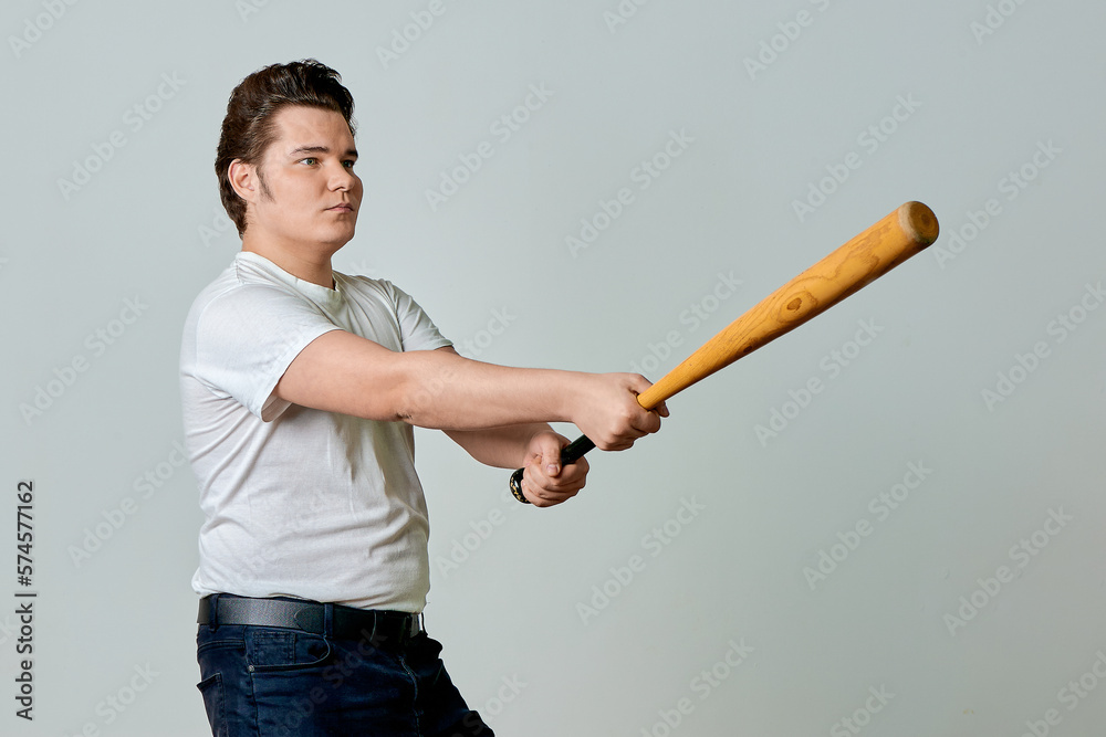 A man with a bat in his hands swings on a gray background A man with a bat in his hands swings on a gray background