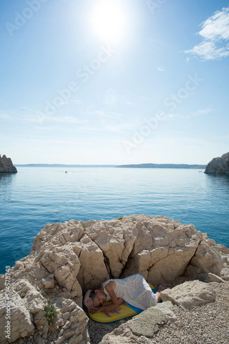 Girl lying down on rocky coastline of Adriatic Sea photo