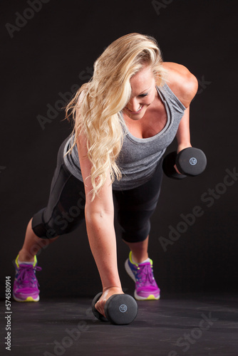 Woman lifting handweight in plank pose photo
