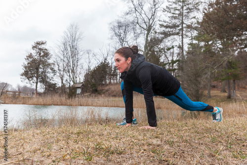 Woman stretching while jogging, Hingham, Massachusetts, USA photo