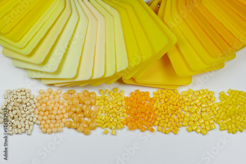 different yellow plastic polymer resin granulates with color samples plates in laboratory photo