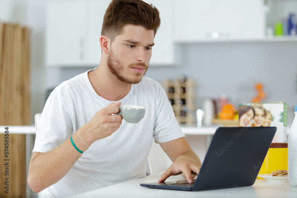 man having a coffee while working on his notebook