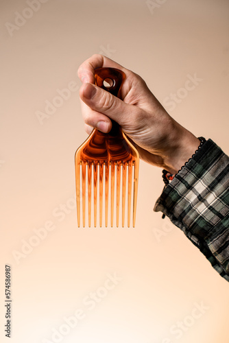 Close-up of male hand holding barber plastic hair styling afro pick comb photo