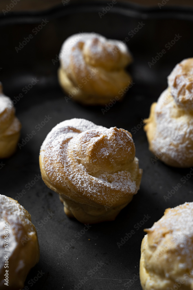 Decorating profiteroles with powdered sugar. Eclairs with icing sugar Decorating profiteroles with powdered sugar. Eclairs with icing sugar