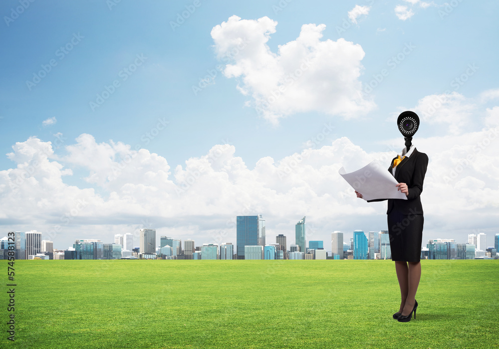 Camera headed woman standing on green grass against modern cityscape Camera headed woman standing on green grass against modern cityscape