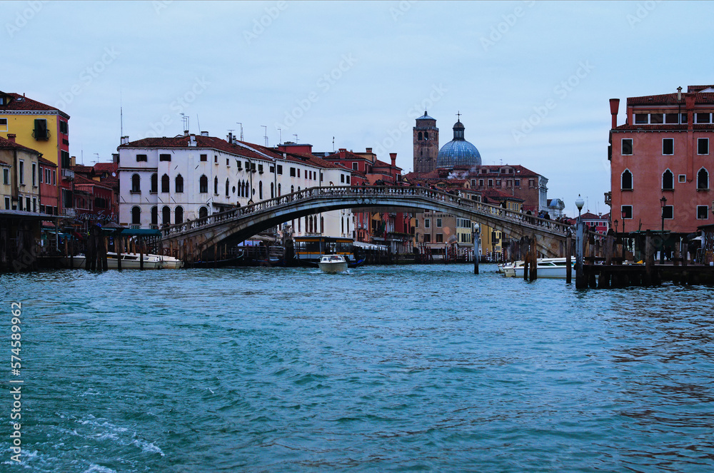 Panoramic landscape view of old brick bridge over canal in Venice. Medieval colorful buildings in the background. Winter drizzle day in Venice. Famous touristic place and travel destination in Europe