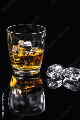 Whisky glass with ice on black background