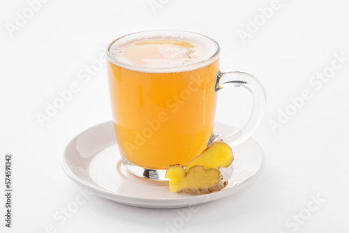 Hot ginger drink with spices in a transparent cup on a white background.