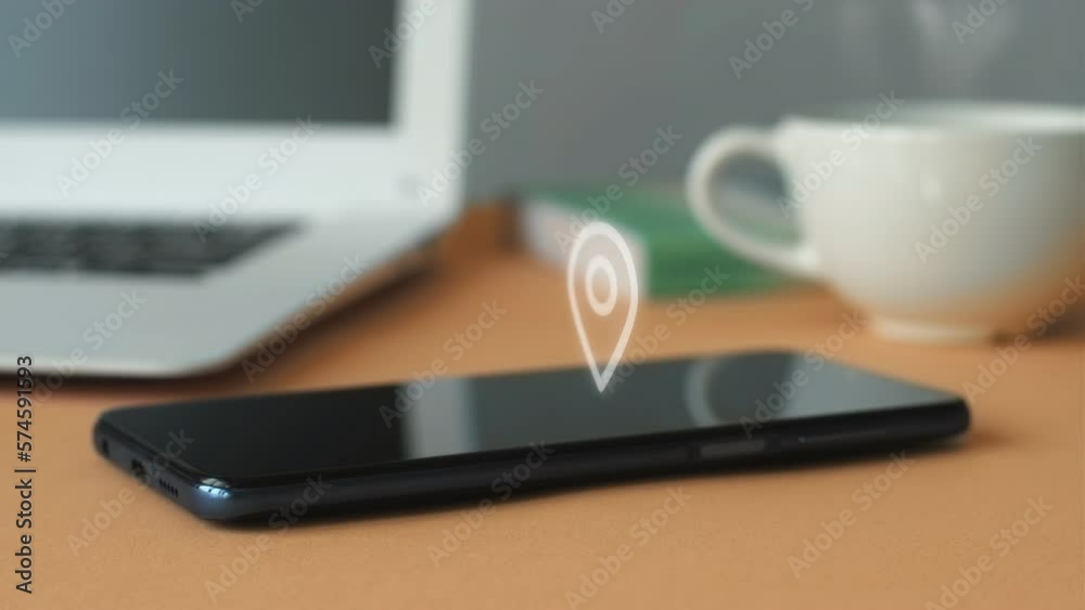 Touch Screen,Wireless Technology,No People,Small Business,Mobile App.Animation of GPS geolocation icon on smartphone display against laptop and coffee cup background in office. Touch Screen,Wireless Technology,No People,Small Business,Mobile App.Animation of GPS geolocation icon on smartphone display against laptop and coffee cup background in office.