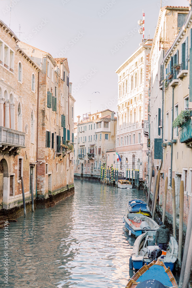 The magic of Venice's city center: a canal runs through the House canyons, boats are crowded together. The water glitters turquoise and the sun reflects off the brick facades.