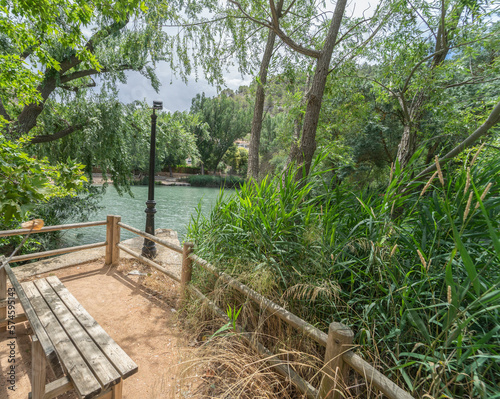 Bench in the recreational area of Alcala del Jucar, overlooking the green and dense vegetation of the Jucar river.
