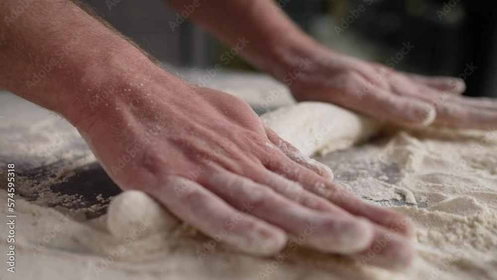 Rolling out dough close-up. A man rolls the dough on a wooden table with a wooden rolling pin. Rolling out dough close-up. A man rolls the dough on a wooden table with a wooden rolling pin.