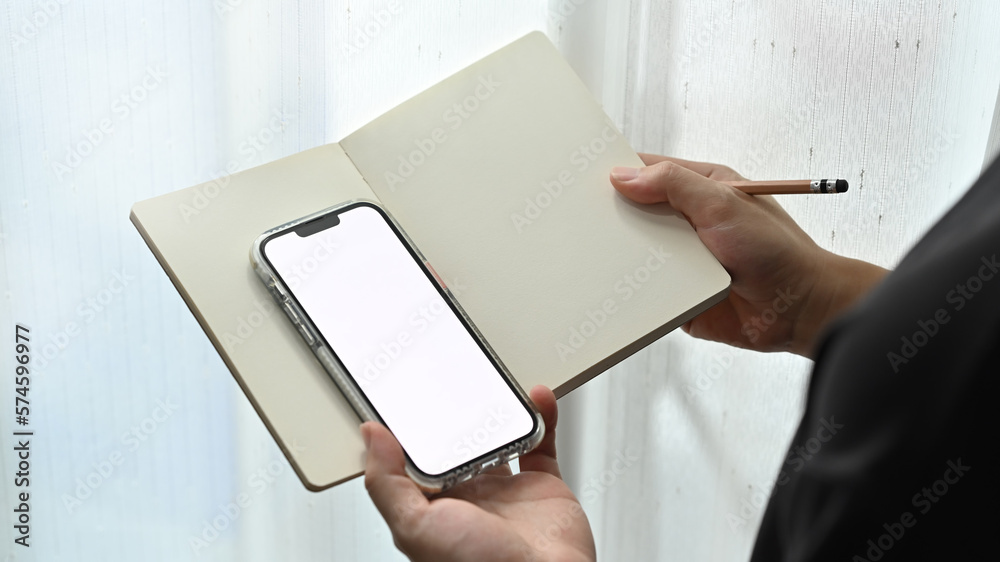 Cropped view of man holding notebook and using smart phone. People, technology and lifestyle concept Cropped view of man holding notebook and using smart phone. People, technology and lifestyle concept