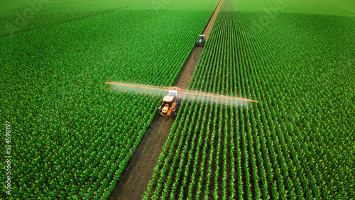 Aerial view of tractor spraying fertilizer on corn fields. 3d render