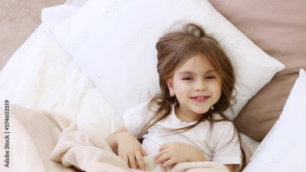 Child wake up. Little girl lies in bed under blanket early morning with shaggy hair on face hard wake up. Child wake up. Little girl lies in bed under blanket early morning with shaggy hair on face hard wake up.