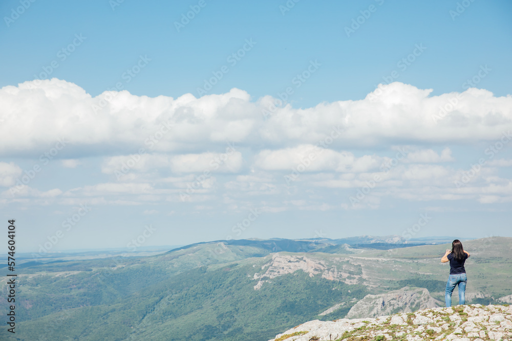 a woman standing on top of a mountain above a blue sky on a hike trip a woman standing on top of a mountain above a blue sky on a hike trip