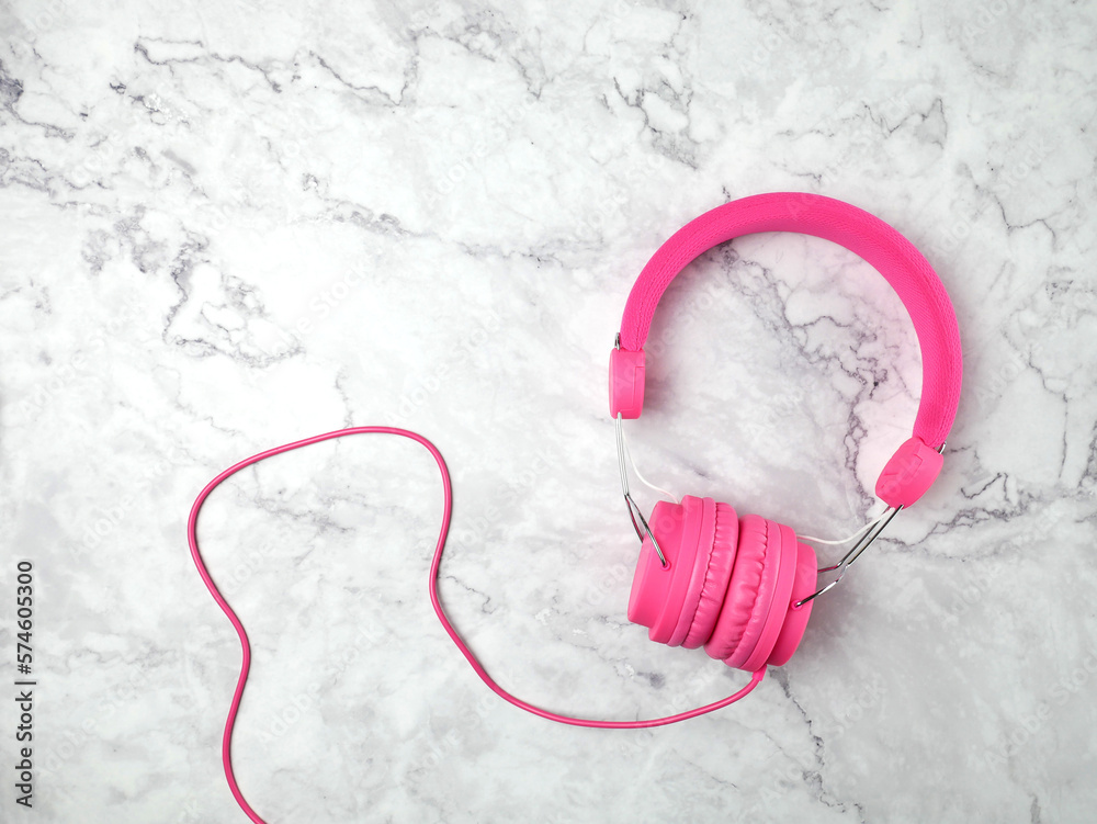 Pink headphones on marble texture background.