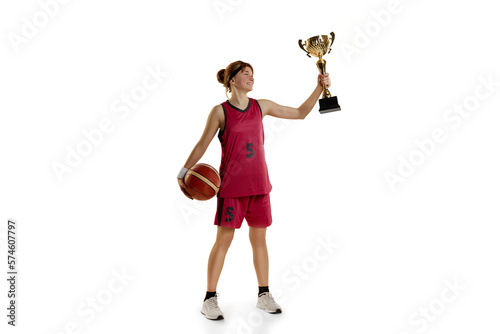 Winning game. Teen girl, basketball player posing with trophy, award isolated over white studio background. Concept of sportive lifestyle, active hobby, health, endurance, competition
