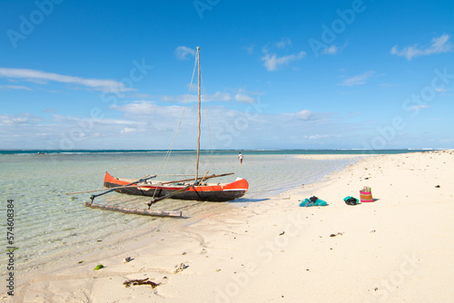 Pirogue boat trip to the Nosy Ve island, Anakao, Madagascar. View of a pirogue boat on a white sand beach with blue sky in the background. 