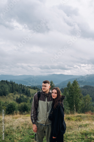 Photo of a beautiful young couple of tourists in the mountains against the background of beautiful views © bodnarphoto