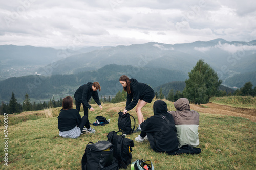 A group of tourists sit on top of a mountain and rest after climbing. Friends on a mountain hike are resting.