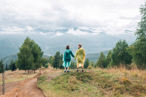 A young couple  a man and a woman holding hands  stand in the mountains against the background of a beautiful landscape during a hike. Tourism of a couple in love in the mountains