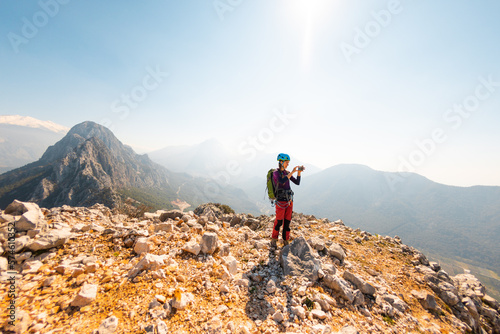 hiking in the mountains. a girl with a backpack takes pictures of the mountains and the sky on the phone from the top of the mountain. climbing and hiking.