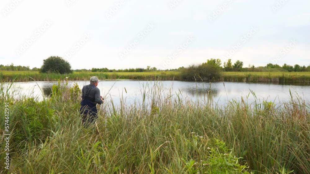 Fisherman fishing from the shore spinning on the lake Fisherman fishing from the shore spinning on the lake