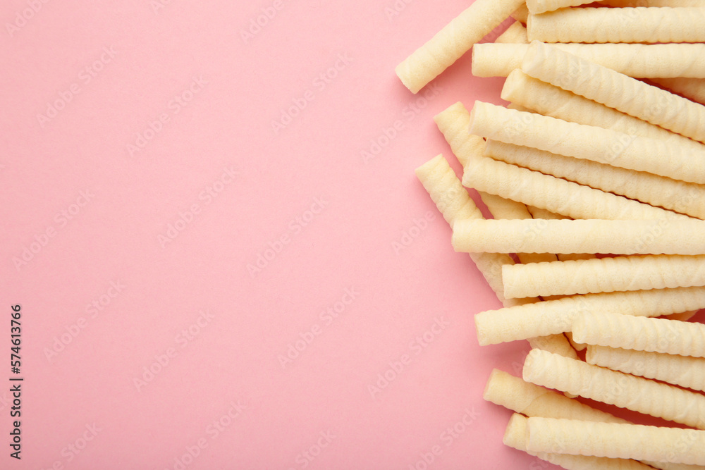 Delicious milk wafer rolls on pink background