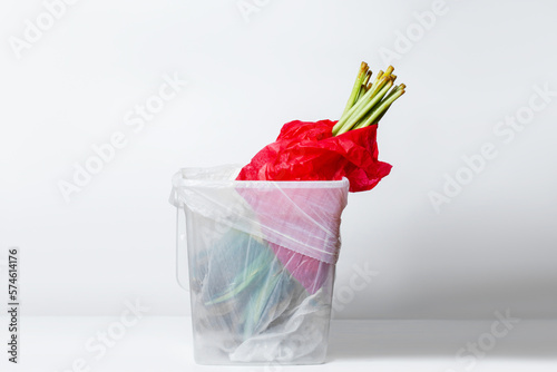 wilted flower. Wilted tulips in red packaging. In the garbage bucket. Inverted down