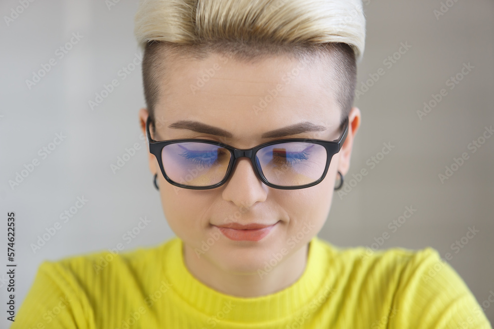 Portrait of beautiful white woman with short hair working on computer. Closeup photo of stylish tom boy female in glasses using a laptop