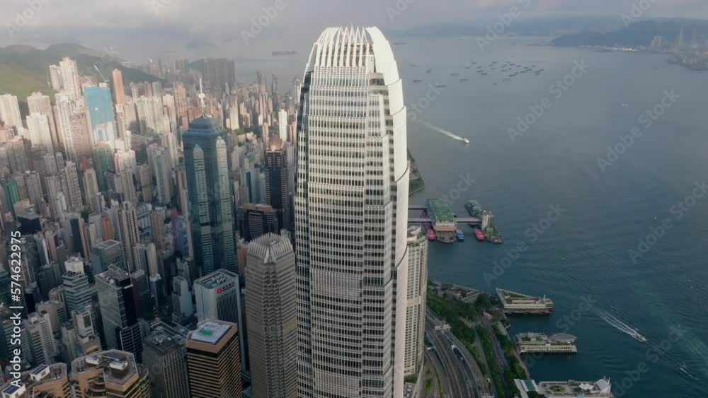 Top of the skyscraper IFC illuminated by the sunlight on a early morning in the skyline of Hong Kong. Drone panning tilt shot
