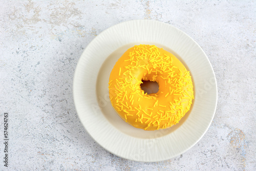 yellow donut with mango taste isolated on white saucer isolated, topview