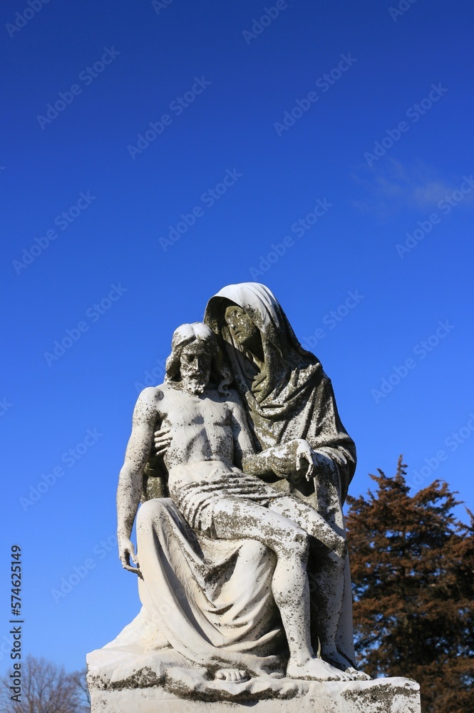 Statue of the Virgin Mary holding Jesus against a blue sky.