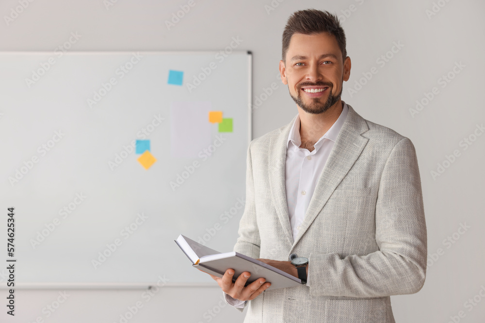 Happy teacher with book at whiteboard in classroom Happy teacher with book at whiteboard in classroom