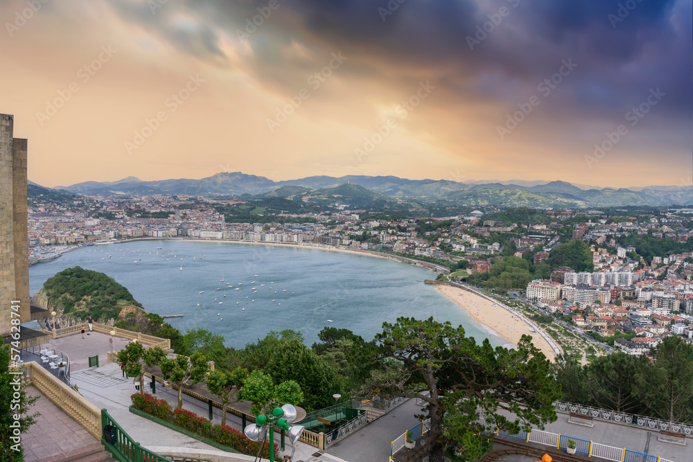 Panoramic aerial view of San Sebastian (Donostia) in the orange sunset with some black clouds. 